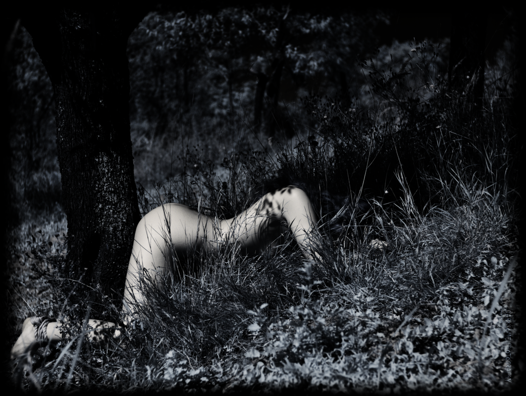 Temné zákoutí s klečící dívkou přivázanou za nohy ke stromu.